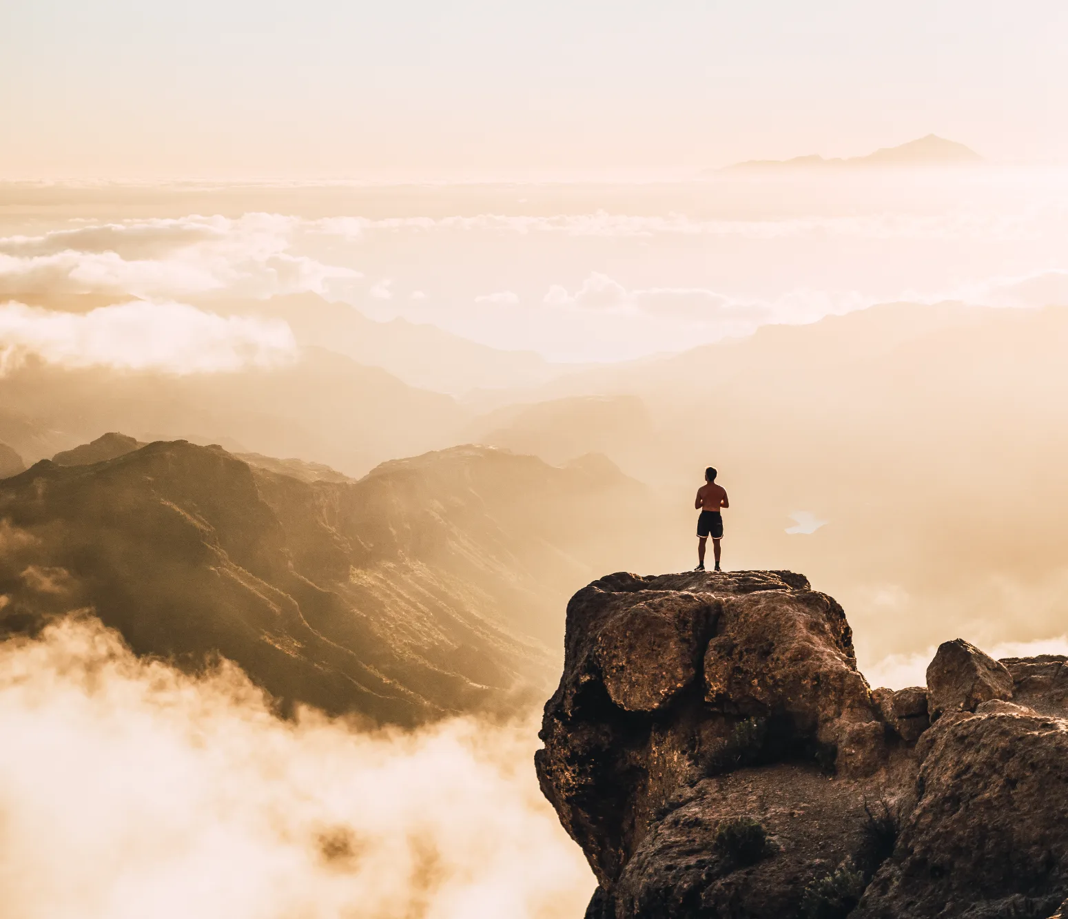 Man sitting on a mountain ledge at sunrise